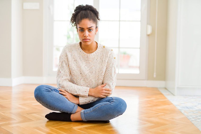 pretty disgruntled woman sitting cross-legged on the floor, looking into camera - victim mentality