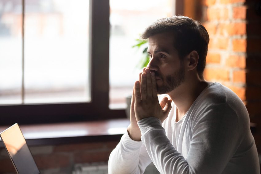 thinking or praying man sitting at desk at home - spouse