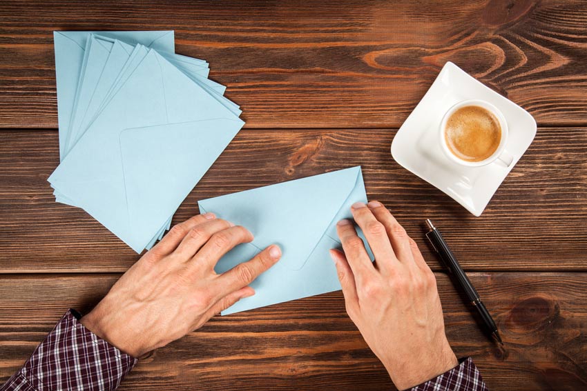 closeup of man's hands sealing blue envelopes - high-stress times