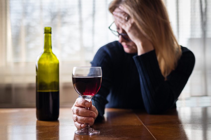 stressed woman drinking red wine at home - alcohol and anxiety
