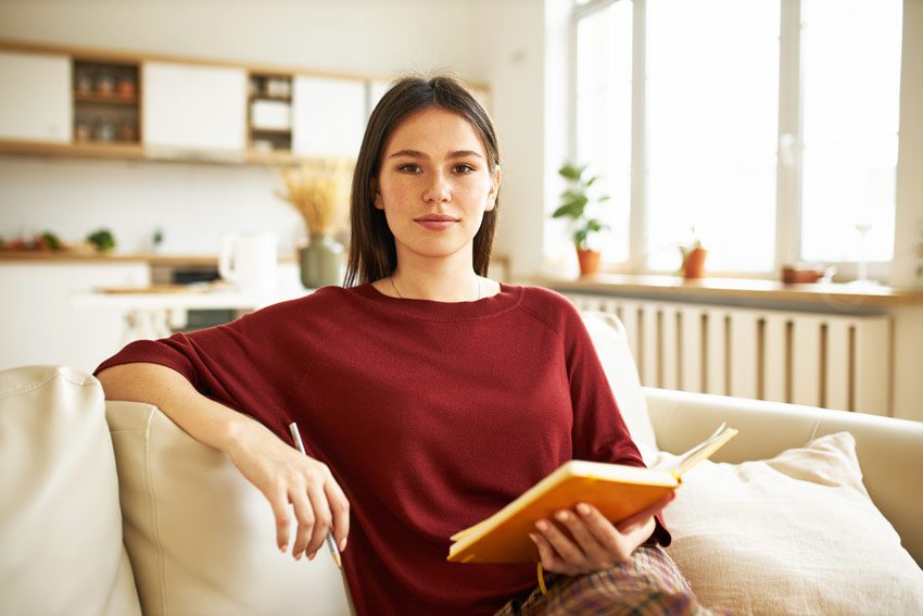 pretty young woman looking at camera, holding planner or journal - recovery goals