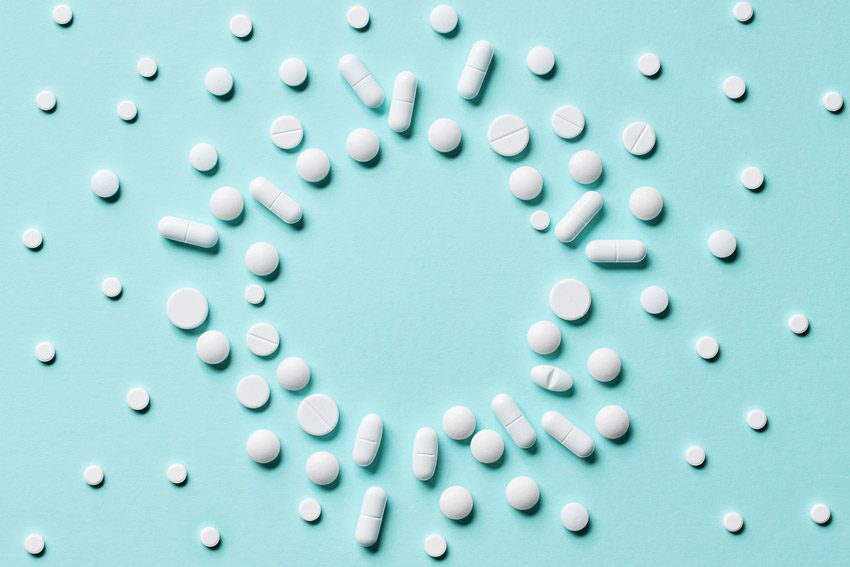 different types of white pills all arranged on a aqua background - benzo addiction